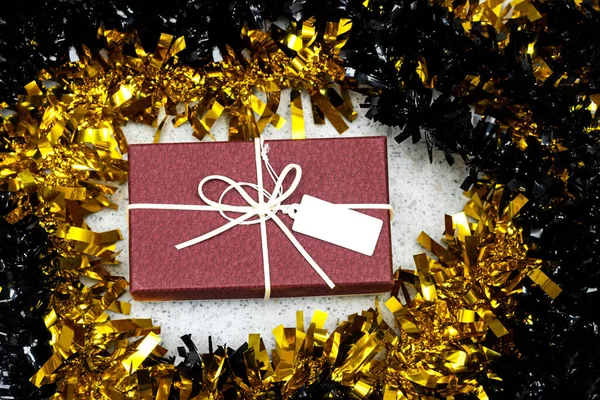 black and golden Tinsel  around gift box with tag, merry Christmas concept