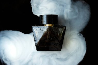 Duman üstünde siyah bir parfüm şişesi
