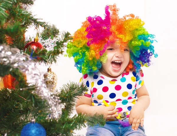 Glad tjej i clown peruk mot bakgrund av jul t — Stockfoto