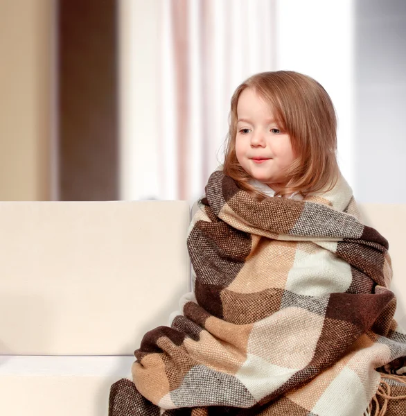 kanepede oturan bir battaniye giyinmiş kız