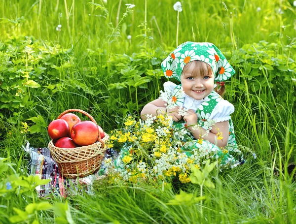 Dziewczynka siedzi na polanie i jedzenia jabłek — Zdjęcie stockowe