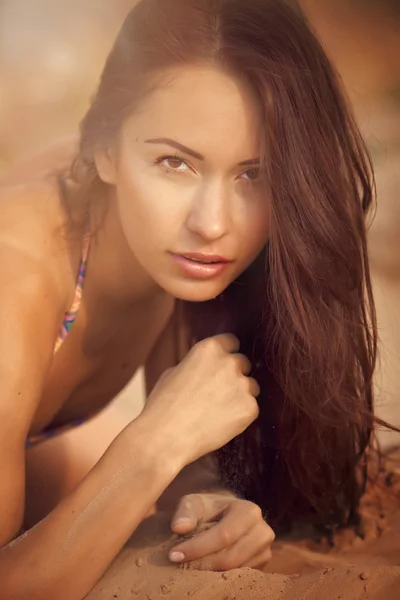 Uma menina bonita em um biquíni derrama areia — Fotografia de Stock