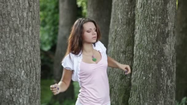 Beautiful girl dances between trees. — Stock Video