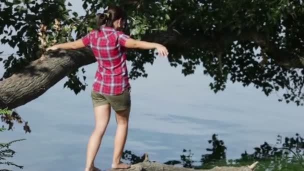 Fille saute sur une branche au-dessus de l'eau — Video