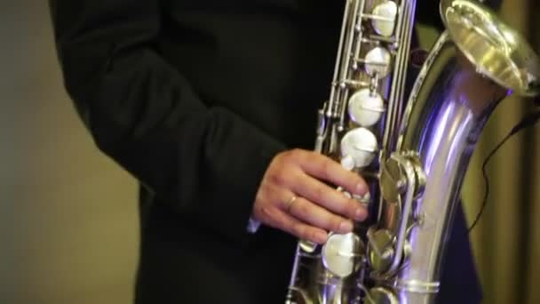 Человек в черном костюме, играет на саксофоне — стоковое видео
