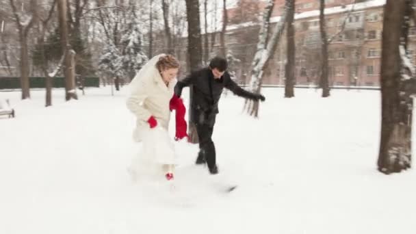 The bride and groom running on snow. — Stock Video