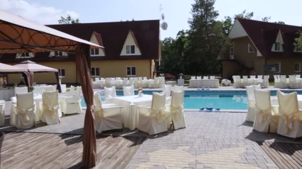 Cámara vuela alrededor de las mesas para su boda Banquete junto a la piscina — Vídeo de stock