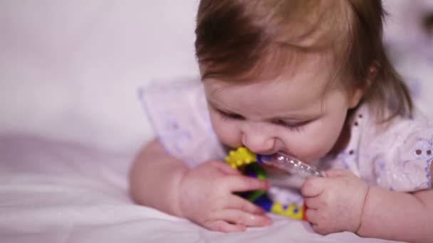 Baby girl smiles and takes in her mouth bright rattle — Stock Video