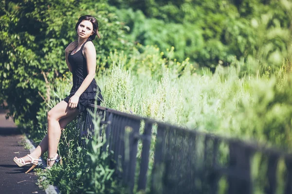 Girl in black dress on fence — Stock Photo, Image