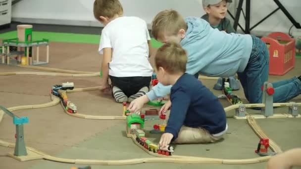 Los niños juegan un gran ferrocarril de juguete en el pabellón interior — Vídeo de stock