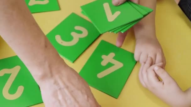 Child with Down syndrome unfolding cards with numbers — Stock Video