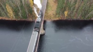 Karelia 'da bir nehrin üzerindeki köprüde bacadan duman çıkan buharlı lokomotif.