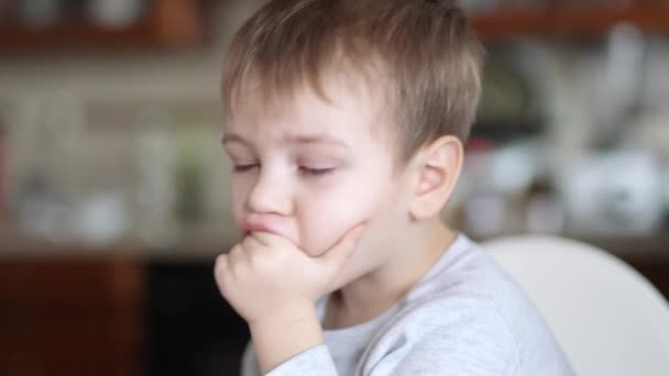 Мальчик с соплями держит руки во рту и отворачивается — стоковое видео