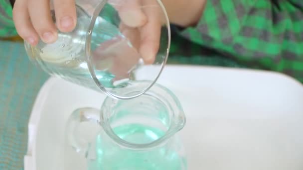 Versare acqua colorata da un bicchiere in un decanter — Video Stock