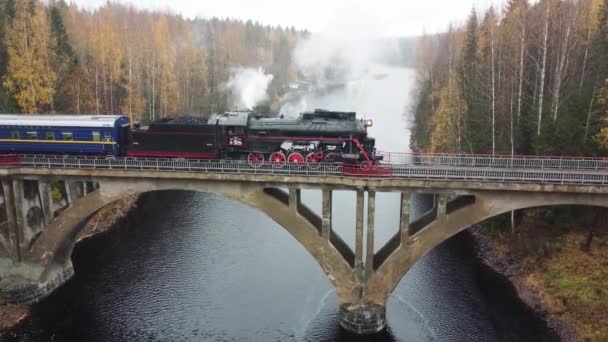 Locomotive à vapeur avec fumée d'une cheminée sur un pont au-dessus d'une rivière en Carélie — Video