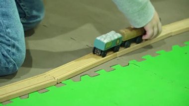 Çocuklar kapalı köşkte büyük bir oyuncak demiryolu oynuyorlar.