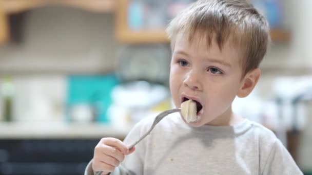 Хвора дитина їсть пельмені на кухні — стокове відео