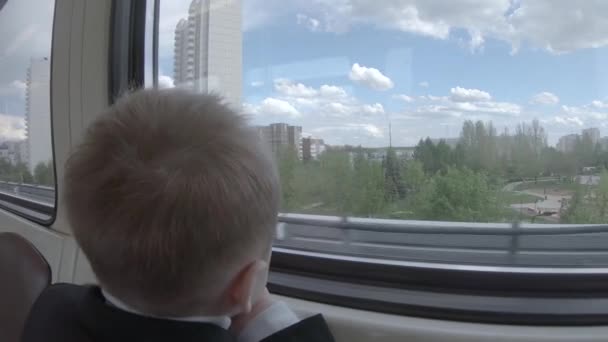 Een jongen kijkt uit het raam — Stockvideo