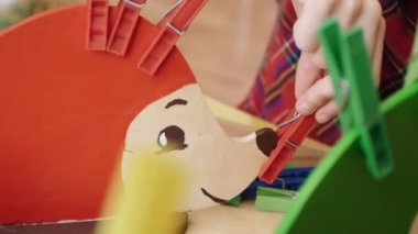 Kartondan bir kirpiye mandalları renklerine göre iliştiriyor