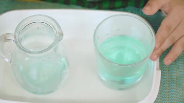 Ρίχνει χρωματισμένο νερό από ένα ποτήρι σε μια καράφα — Αρχείο Βίντεο