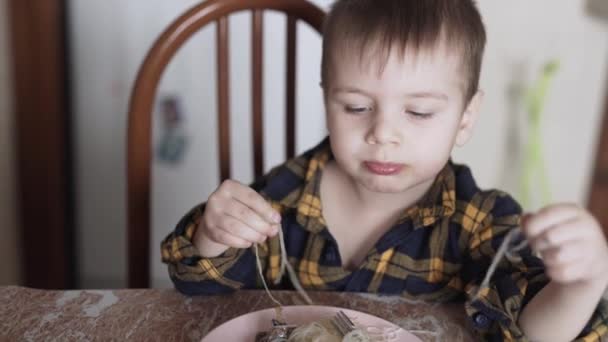 A criança come macarrão chinês com as mãos — Vídeo de Stock