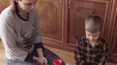 Anne ve oğul yerde top labirenti oynuyorlar.