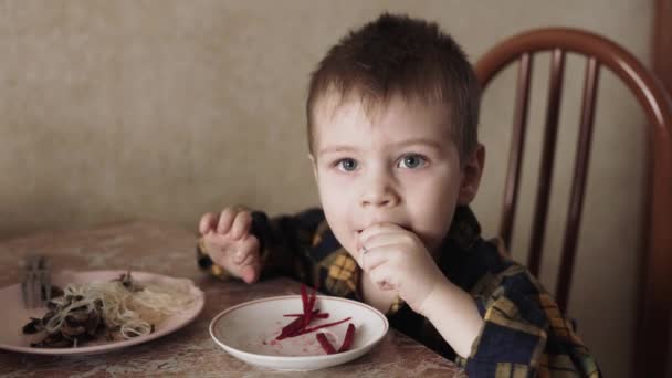 Bir çocuk elleri mutfakta pancar yer. — Stok video