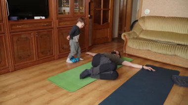 Oğlu ve babası minderde yoga yapıyor.