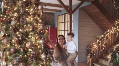 Anne ve oğlu yeni yıl ağacının yanında oynuyorlar.