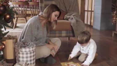Anne ve oğlu yılbaşı ağacının yanında bulmaca topluyor.