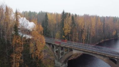 Karelia 'da bir nehrin üzerindeki köprüde bacadan duman çıkan buharlı lokomotif.