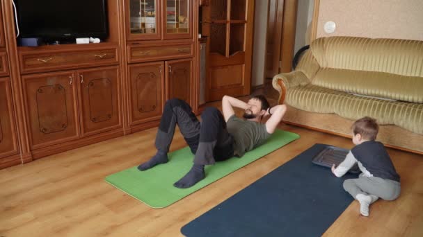 Hijo y papá hacen yoga en la alfombra — Vídeo de stock