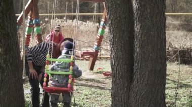Kız salıncakta bir çocuğu yuvarlıyor