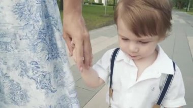 Bir çocuk annesiyle el ele yürüyor.