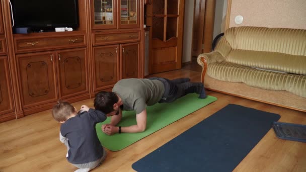 Syn i tata ćwiczą jogę na macie. — Wideo stockowe