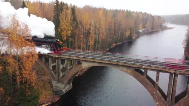 Паровой паровоз с дымом из трубы на мосту через реку в Карелии — стоковое видео