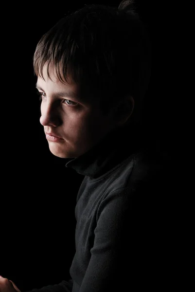 Sad teenage boy in black, low key — Stock Photo, Image