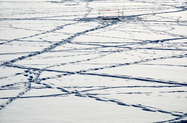 Couverture de neige avec de nombreuses traces et un trou de glace — Photo