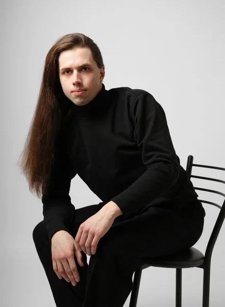 Young man with long hair in black — Stock Photo, Image