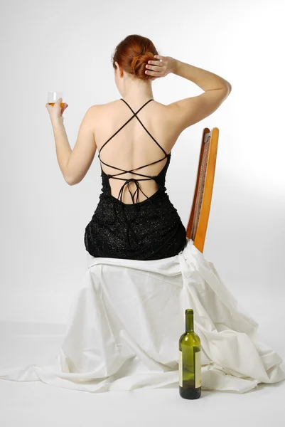 Young woman sitting with wineglass, rear view — Stock Photo, Image