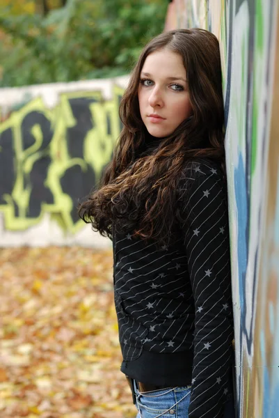 Teenage sad girl near graffiti wall