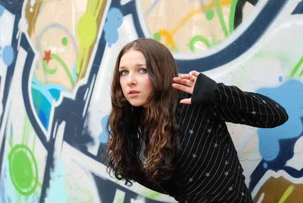 Adolescent fille écoute contre graffiti mur — Photo