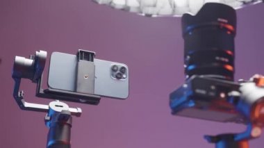 ABD - New York, 09.25.2021: Pembe bir arka planda izole edilmiş dengeleyiciler tarafından düzeltilen yeni akıllı telefon ve kamerayı kapatın. Başla. Video ve fotoğraf çekimi için yeni aygıtların sunumu.