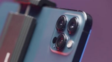 Rusya - Moskova, 09.28.2021: Steadicam tarafından düzeltilen yeni bir Iphone 13 maksimum güvenlikli kameraya aşırı yakın çekim. Başla. Mor duvar arkaplanında izole edilmiş yeni akıllı telefon.