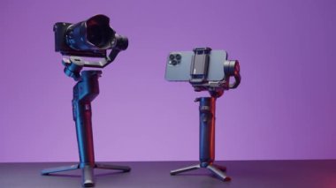 ABD - New York, 09.25.2021: Pembe bir arka planda izole edilmiş dengeleyiciler tarafından düzeltilen yeni akıllı telefon ve kamerayı kapatın. Başla. Video ve fotoğraf çekimi için yeni aygıtların sunumu.