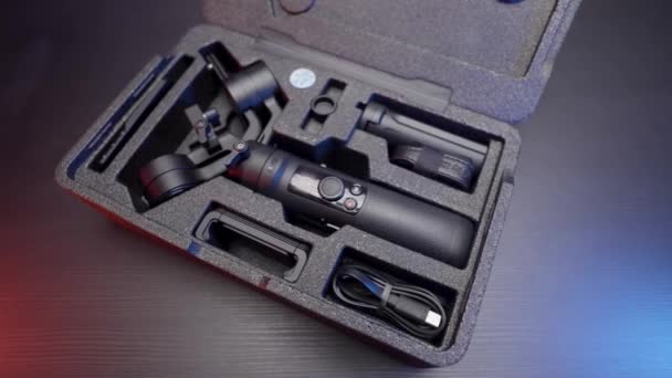 Close up of new smartphone stabilizer inside a case. Action. New professional steadicam for shooting lying on wooden table background. — Stock Video