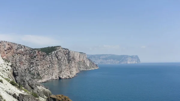 Αεροφωτογραφία της βραχώδους ακτής και της γαλάζιας θάλασσας. Πάμε. Πετώντας πάνω από απότομες πλαγιές μιας οροσειράς, βράχια πάνω από ήρεμη επιφάνεια του νερού, καλοκαιρινό τοπίο της φύσης. — Φωτογραφία Αρχείου