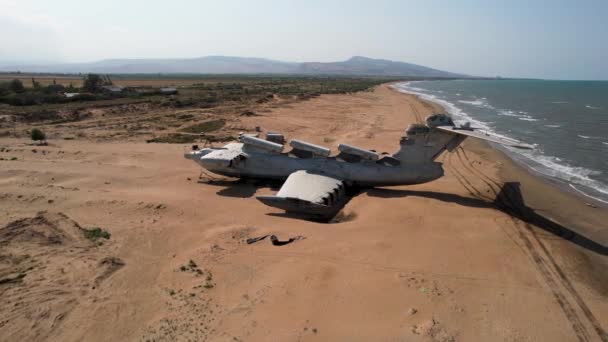 Letecký pohled na zničené opuštěné letadlo nalezené na neobydleném ostrově poblíž moře na pozadí modré oblohy. Akce. Pojetí katastrofy a smrti. — Stock video