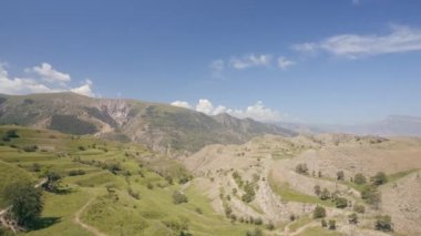 Güneşli bir günde güzel bir vadiyle muhteşem manzaranın havadan görüntüsü. Başla. Mavi bulutlu arka planda, yaz dağlarının üzerinde uçuyor..