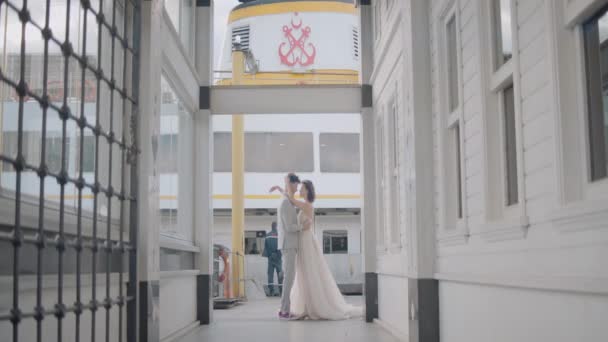 Newlyweds on background of pier. Action. Beautiful newlyweds pose between city buildings. Stylish newlyweds hug on background of city pier in cloudy weather — Stock Video